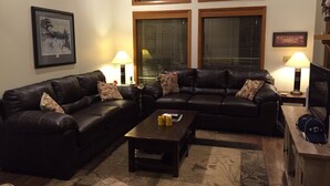 A living room with two black leather sofas, a wooden coffee table, and two lamps.