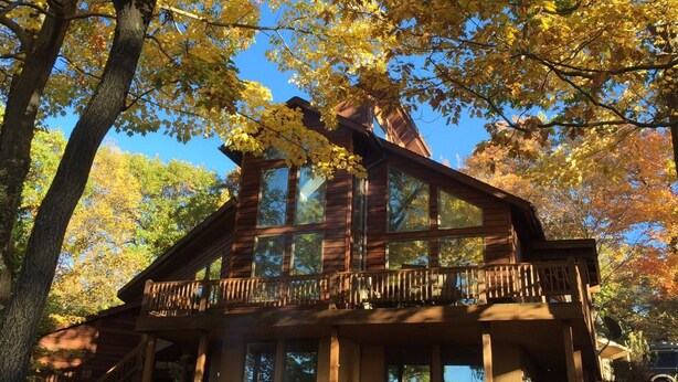 A cabin with a balcony, large windows, and a wooden exterior.