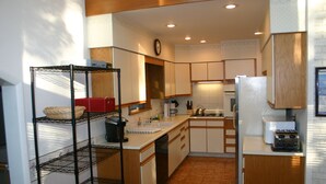 A compact kitchen with white cabinets, a wooden countertop, a sink, a stove, and a clock on the wall.