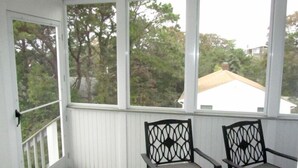 A room with two chairs and a view of trees and a house through large windows. - Attractive 3BR Cape Home Close to Indian Neck Beach (1430) (Wellfleet)