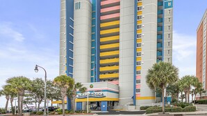 Un hotel de varios pisos con un diseño arquitectónico distintivo, que combina líneas curvas y rectas, y una variedad de colores en su fachada.