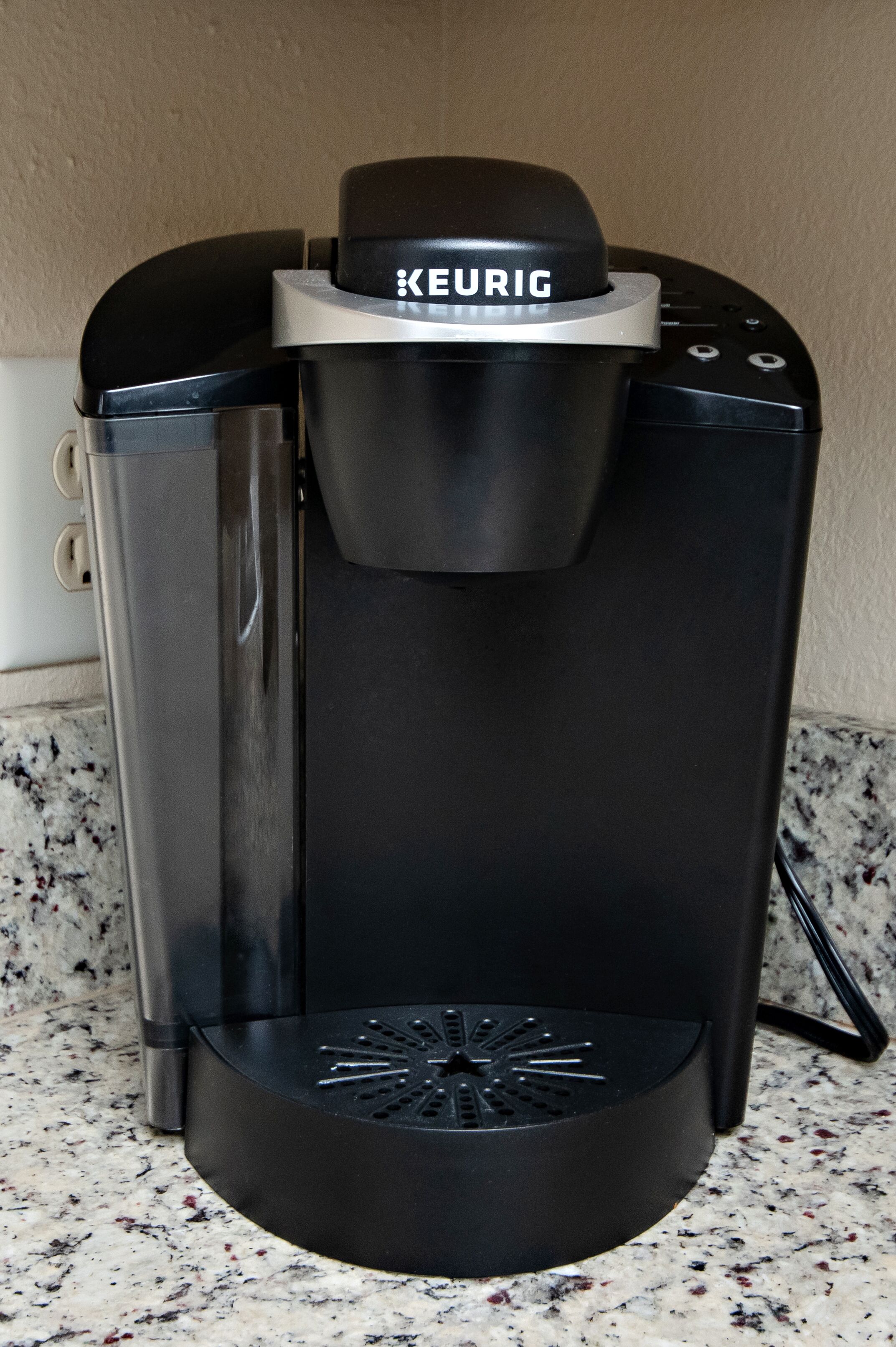 Eine schwarze Keurig-Kaffeemaschine mit einem Wasserbehälter aus Edelstahl und einer Auffangschale.