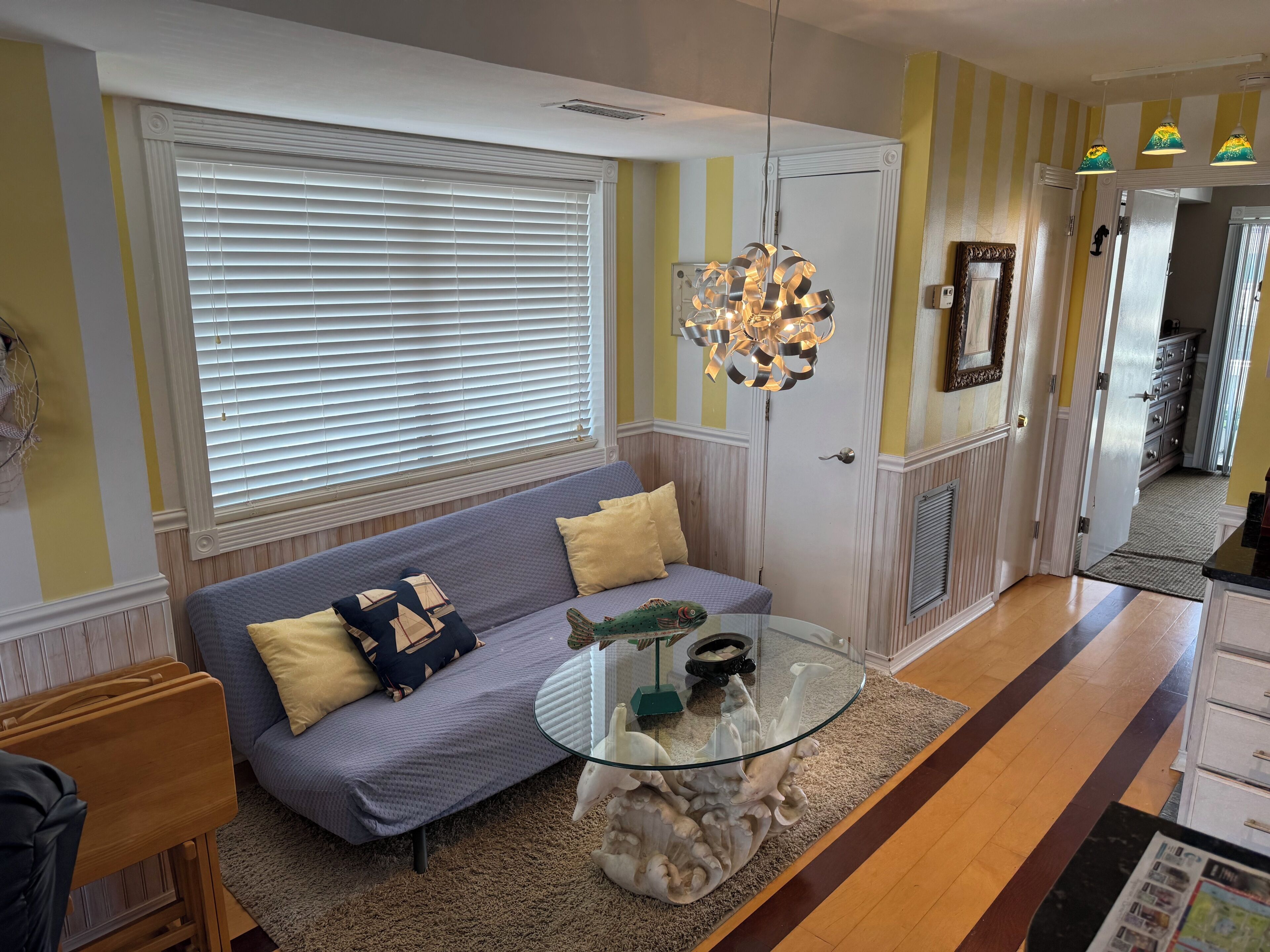A living room with a sofa, a glass coffee table, and a decorative light fixture.
