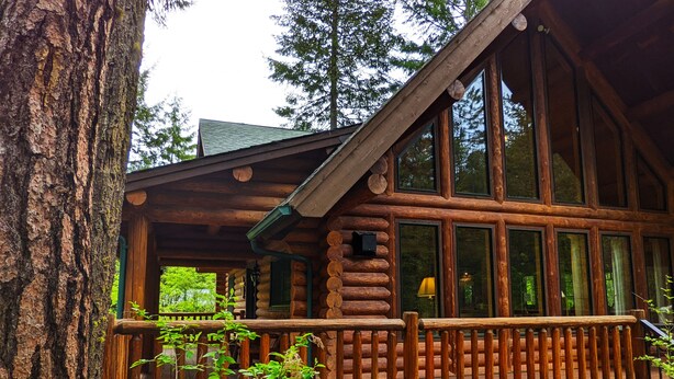 A log cabin with a wooden porch and large windows. - Beautiful Log Home near Leavenworth, WA. Nestled In The Woods (Peshastin)