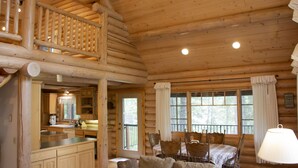 A log cabin interior with a dining area, kitchen, and a balcony. - Beautiful Log Home near Leavenworth, WA. Nestled In The Woods (Peshastin)