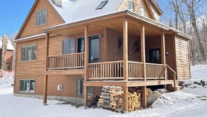 A two-story wooden cabin with a covered porch and a chimney. - On Mountain Home, Spectacular Mountain Views, Ski to the Door (Carrabassett Valley)