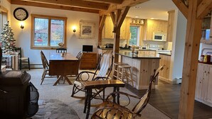 A cozy interior with a wooden dining area, a kitchen with wooden cabinets, and a Christmas tree. - On Mountain Home, Spectacular Mountain Views, Ski to the Door (Carrabassett Valley)