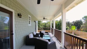 A covered porch with wicker furniture, a ceiling fan, and a view of the backyard.