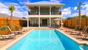 A two-story house with a swimming pool, outdoor furniture, and a wooden fence.