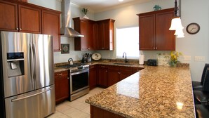 A kitchen with granite countertops, stainless steel appliances, wooden cabinets, and a large island.