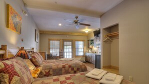 Une chambre confortable avec deux lits, un ventilateur de plafond et un coin cuisine.
