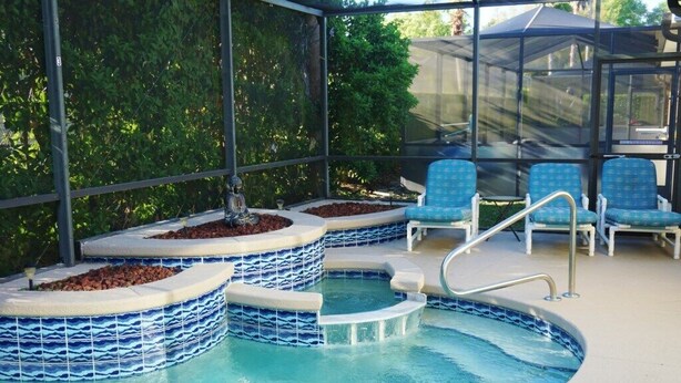 A pool area with a glass-enclosed deck, blue chairs, and a small hot tub. - Quiet and beautiful place (Kissimmee)