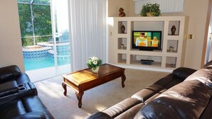 A living room with a TV, a pool, and a sofa. - Quiet and beautiful place (Kissimmee)