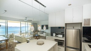 A modern kitchen with a large island, stainless steel appliances, and a view of the sea.