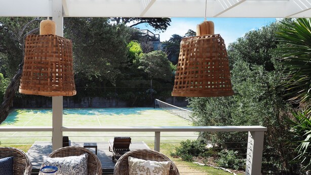 An outdoor seating area with wicker furniture, a table with drinks, and a view of a tennis court. - SORRENTO TENNIS RETREAT - 4BR and tennis court, just 5min walk to Sorrento strip (SORRENTO)