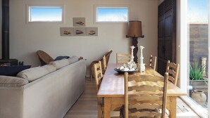A cozy living area with a sofa, a wooden dining table with chairs, and a large window providing natural light. - SORRENTO TENNIS RETREAT - 4BR and tennis court, just 5min walk to Sorrento strip (SORRENTO)