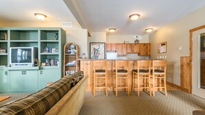 A compact living space with a kitchenette, a sofa, a TV, and a bookshelf. - Large balcony, walk out condo on trails - Pet friendly! (Silver Star Mountain)