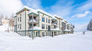 A multi-story hotel with balconies, surrounded by snow-covered trees. - Large balcony, walk out condo on trails - Pet friendly! (Silver Star Mountain)