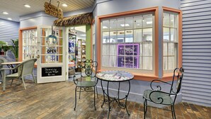 Une charmante boutique avec une enseigne indiquant « QUAY STORE » et une vitrine où l’on peut lire « OUVERT » et « SACS SURPRISE DE BIJOUX, 1,00 $ ».
