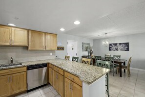 Una cocina moderna con encimeras de granito, armarios de madera y lavavajillas.