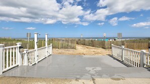 Une promenade en bois menant à une plage, avec un ciel dégagé.