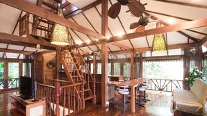 A spacious wooden interior with a staircase, a dining area, and a cozy seating area.