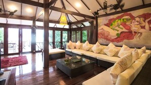 A spacious living area with a large sofa, a coffee table, and a mural on the wall.