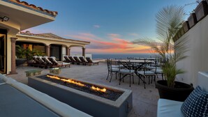 A rooftop terrace with a fire feature, lounge chairs, and outdoor seating.