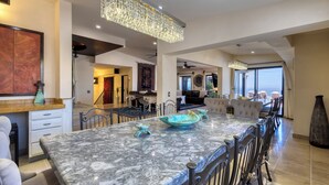 A spacious kitchen with a marble countertop, modern lighting fixtures, and a view to the outside.
