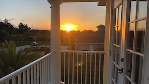 Un balcon offrant une vue sur le coucher de soleil au-dessus d’un quartier résidentiel.