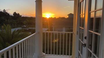 A balcony with a view of the sunset over a residential area.