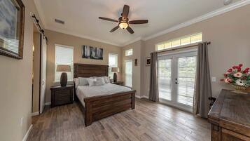 A bedroom with a wooden bed, a ceiling fan, and a view of the outdoors through a sliding glass door.