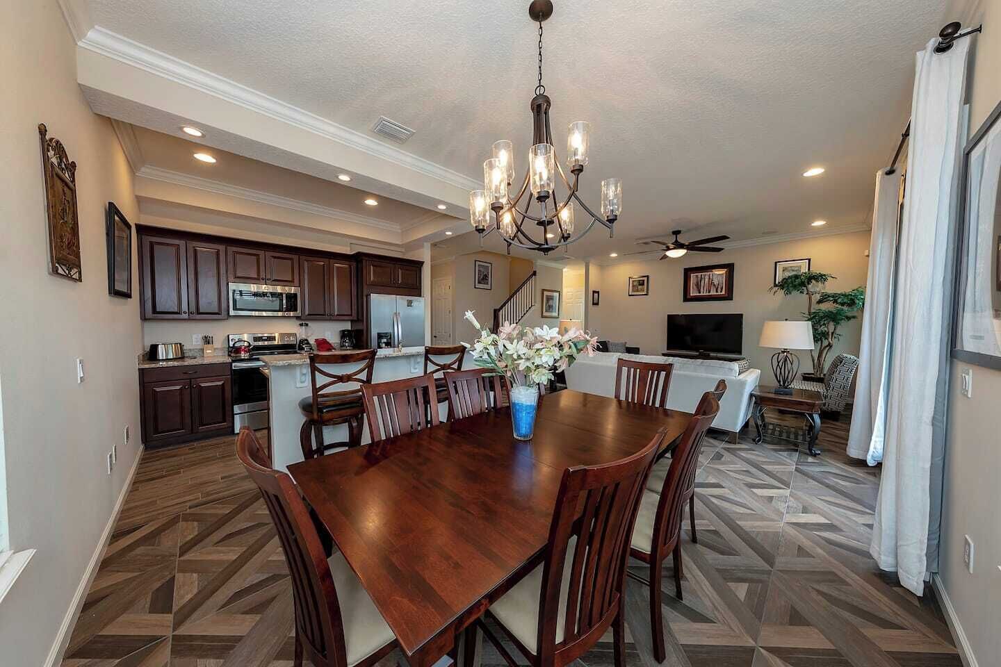 A spacious kitchen with dark wooden cabinets, a central island, and a dining area with a wooden table and chairs.