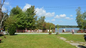 A grassy area with a wooden fence, benches, and a view of a lake.