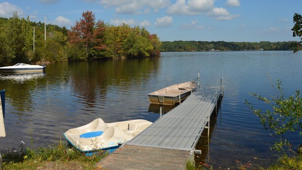 A calm lake with a wooden dock and a rowboat.