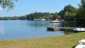 A lakeside view with a dock, boats, and lounge chairs.