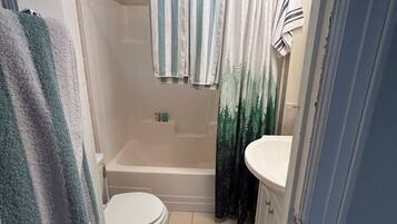 Une salle de bain avec des toilettes, une baignoire et un lavabo.