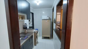 A narrow kitchen with a microwave, sink, and cabinets. - Come and enjoy this paradise in a comfortable 3-bedroom apartment on Forte beach. (Centro)