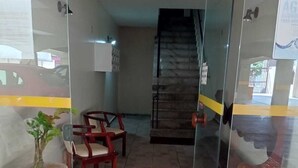 A hallway with a potted plant, two wooden chairs, and a staircase leading to an upper level. - Come and enjoy this paradise in a comfortable 3-bedroom apartment on Forte beach. (Centro)
