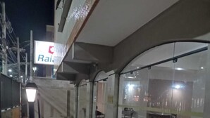 A nighttime view of a building with a glass facade, outdoor seating area with chairs, and a staircase leading to an upper level. - Come and enjoy this paradise in a comfortable 3-bedroom apartment on Forte beach. (Centro)