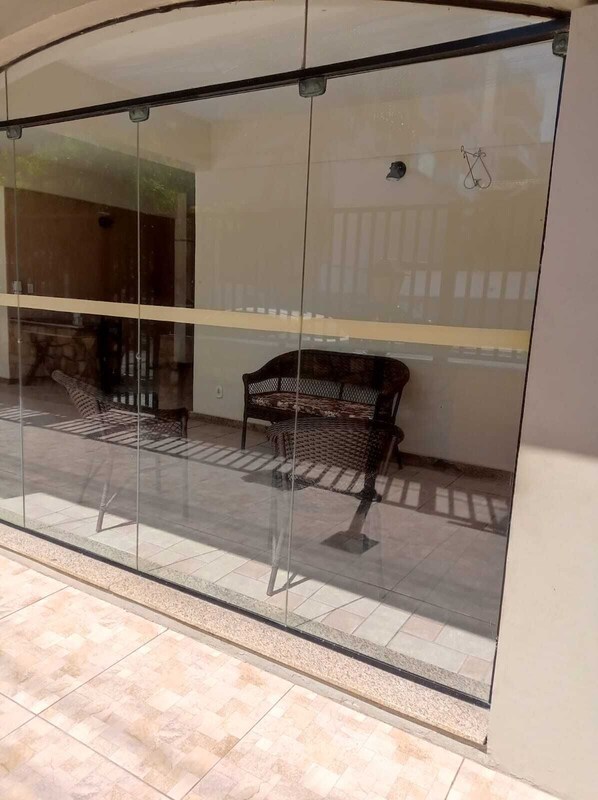 A glass-walled room with a bench and a chair, tiled floor, and a visible door.