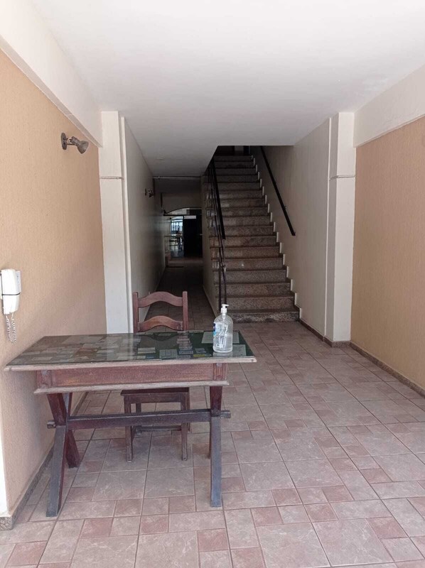 A spacious room with a dining table and chairs, a staircase leading to an upper floor, and a visible kitchen area. - Come and enjoy this paradise in a comfortable 3-bedroom apartment on Forte beach. (Centro)