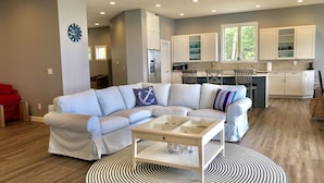A modern living room with a sectional sofa, a glass coffee table, and a patterned rug. - Loving Life at the Lake (Black River)