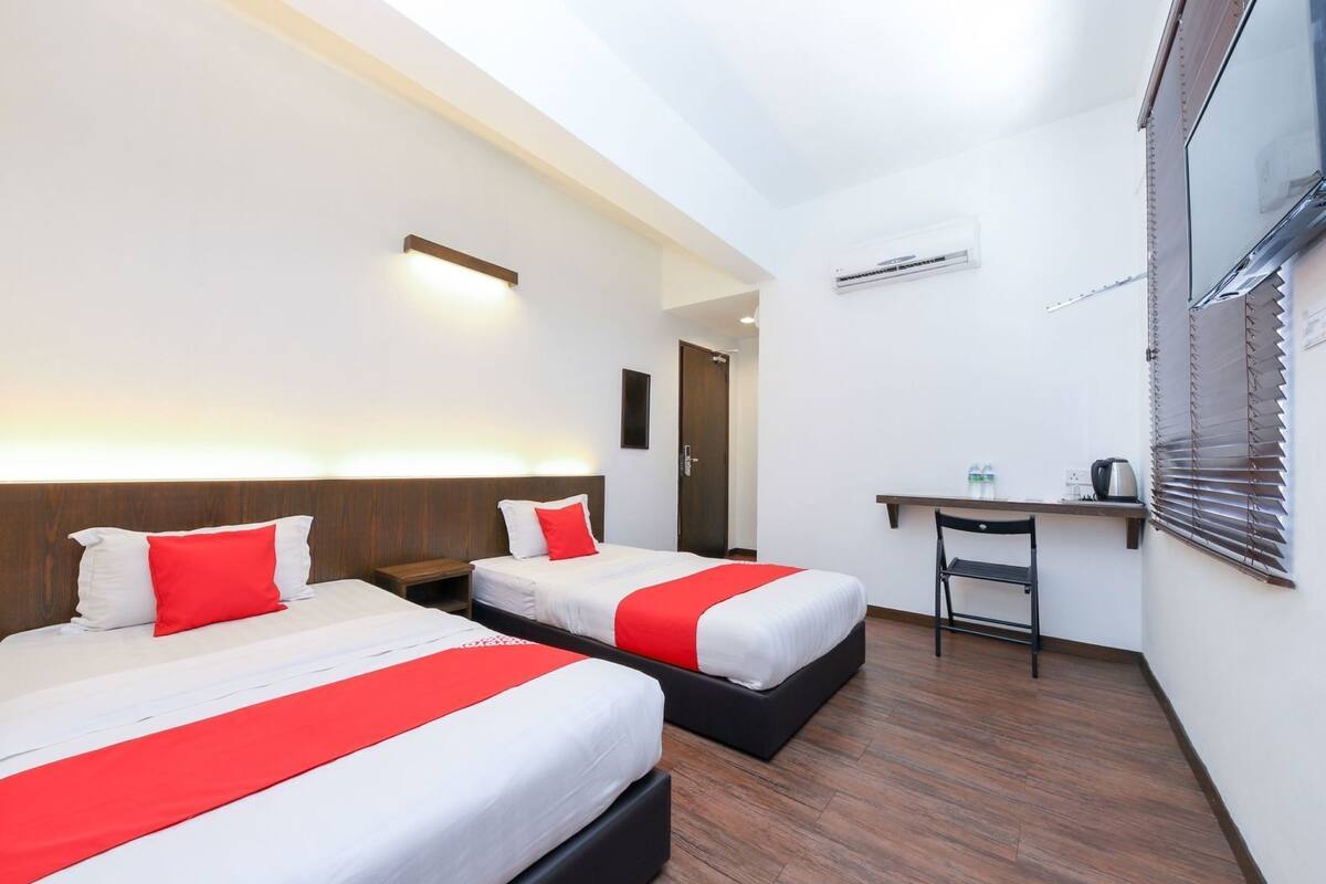 Een hotelkamer met twee bedden, een bureau en een stoel.