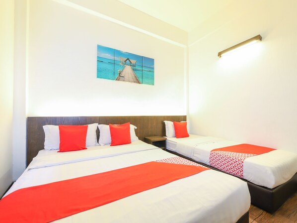 Habitación de hotel con dos camas, cada una con ropa de cama blanca y roja, un cabecero de madera y una mesita de noche. En la pared, un cuadro de un muelle y el océano.