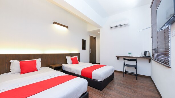 Habitación de hotel con dos camas, un escritorio y una silla.