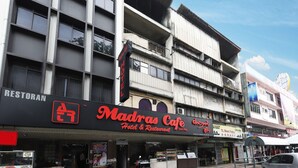 Un edificio de varios pisos con un letrero llamativo que dice 'Madras Cafe Hotel & Restaurant'.