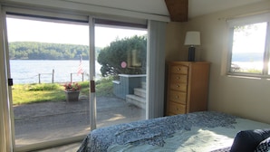 Quarto com uma cama grande, uma cômoda e vista para um lago através de uma porta de correr.