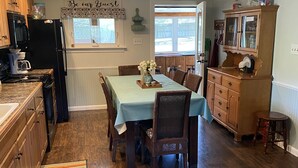 A kitchen with wooden cabinets, a dining table with chairs, a striped rug, and a kitchen island with a sink.