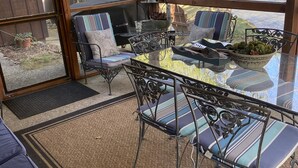 An outdoor patio with metal furniture, a glass table, and a grill.